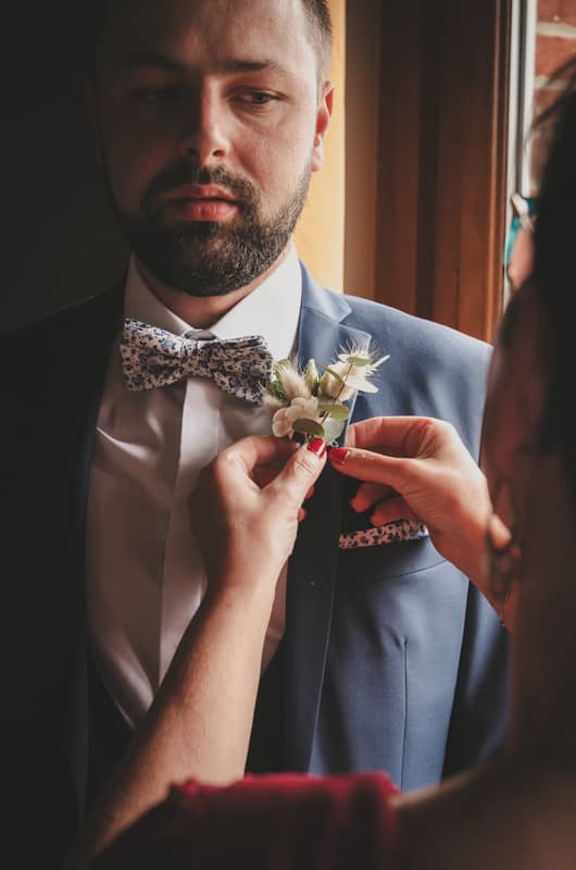 Préparatifs de mariage : la mère du marié place la fleur sur sa veste