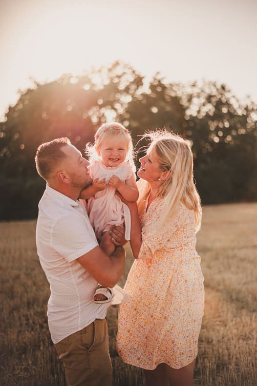 photographe de famille - séance famille - enfant dans les bras de ses parents champs blés