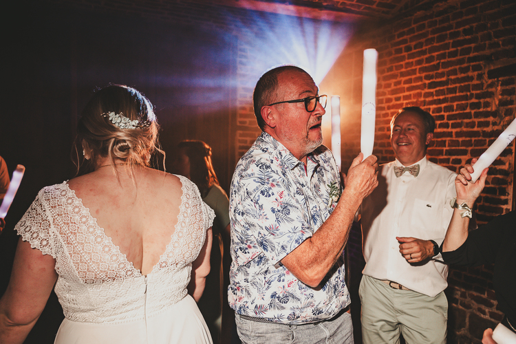 Les invités et la mariée lors d’une célébration de mariage, tenant des bâtons lumineux pour danser sur la piste