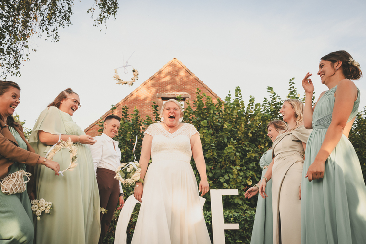 Un moment de mariage capturé en plein air, des couronnes de fleurs passent au dessus de la mariée