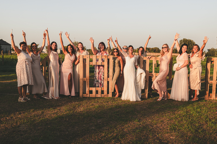 Un groupe de personnes en tenue de soirée derrière une clôture en bois, levant les bras en signe de célébration.