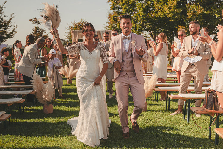 La mariée et le marié marchent ensemble dans l’allée lors d’une cérémonie de mariage en plein air.
