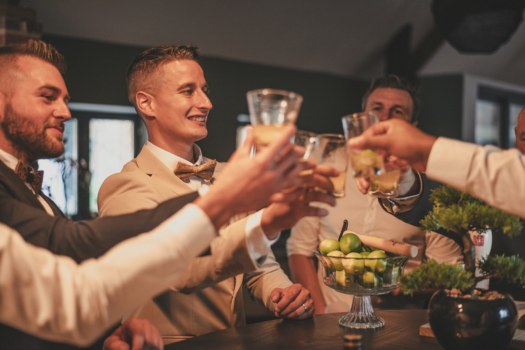 Les invités en tenue formelle levant leurs verres pour un toast lors d’un mariage.