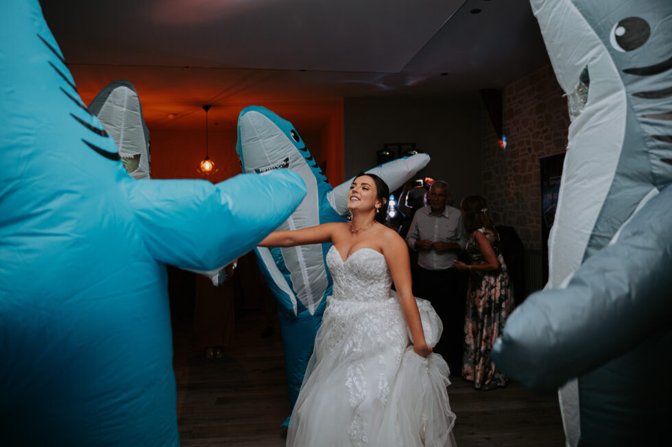 La mariée s'éclate sur la piste de danse entourée de deux invités déguisés en requins gonflables bleus.