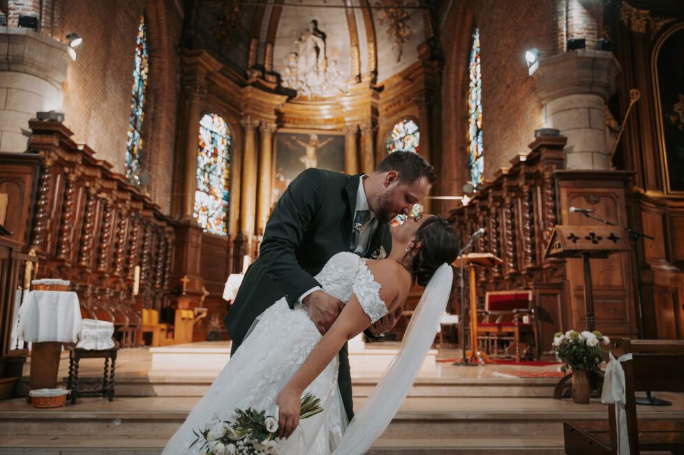 Le marié bascule romantiquement la mariée en arrière pour un baiser passionné au milieu de l'église.
