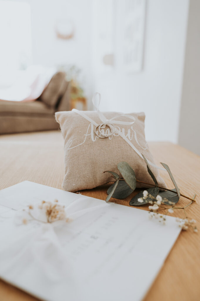Coussin d'alliances en lin avec inscription "Amour", eucalyptus et faire-part pour Rachel et Arthur.