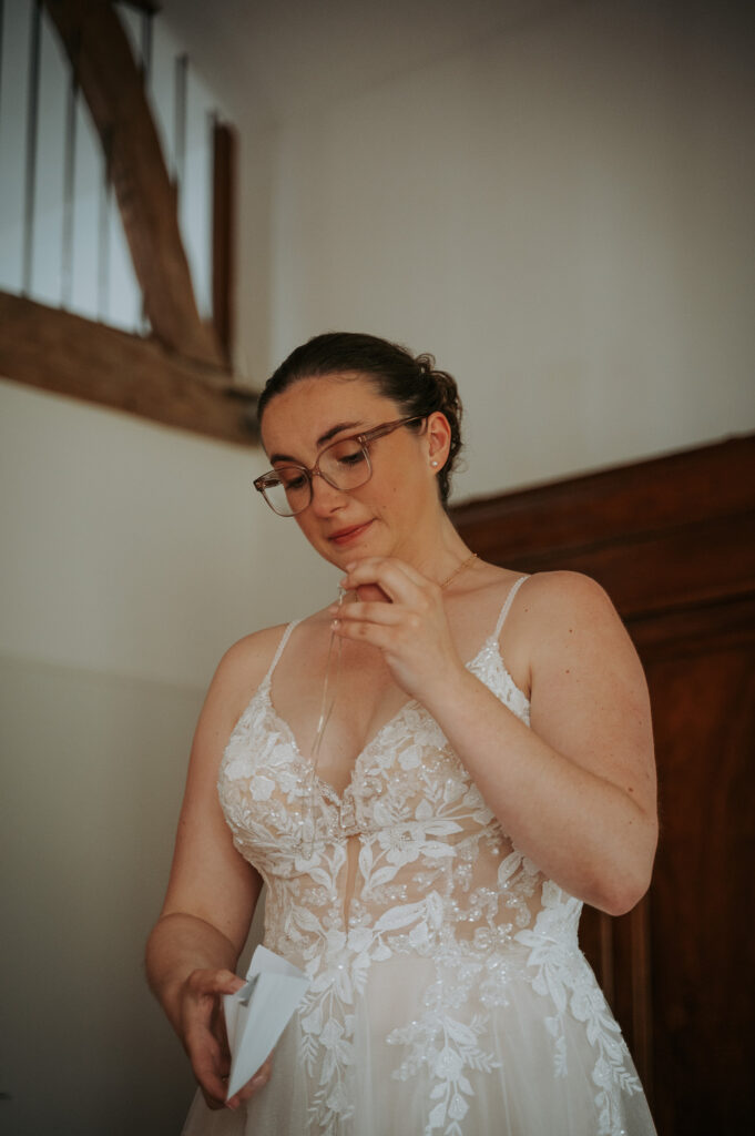Mariée émue découvrant un détail de mariage précieux durant ses préparatifs.