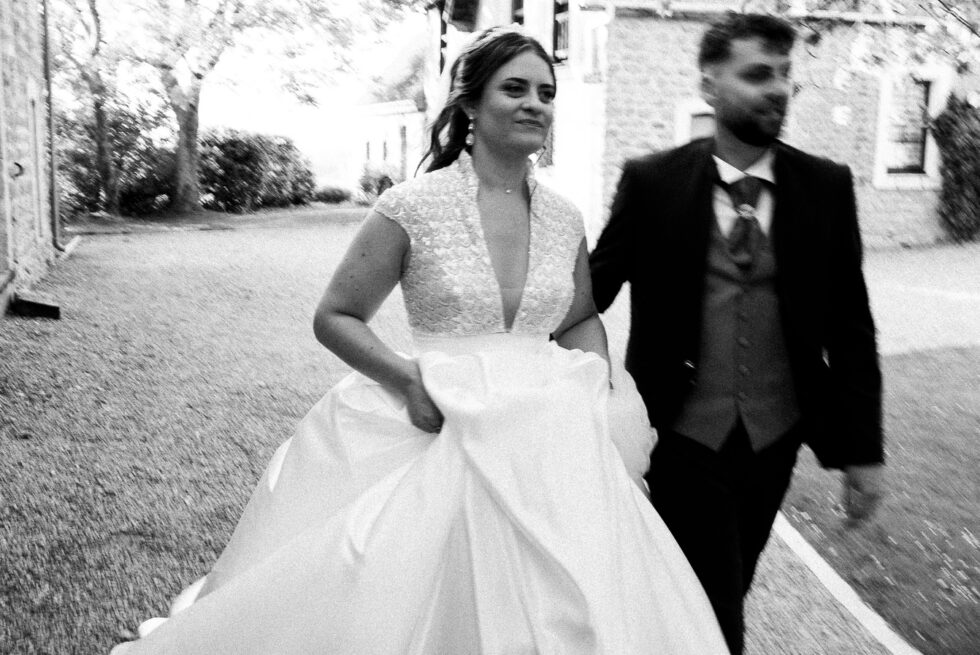 Photo floue artistique en noir et blanc d'un couple de mariés courant main dans la main.