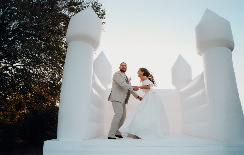 Les mariés sautent et s'amusent dans un château gonflable blanc installé pour le mariage.
