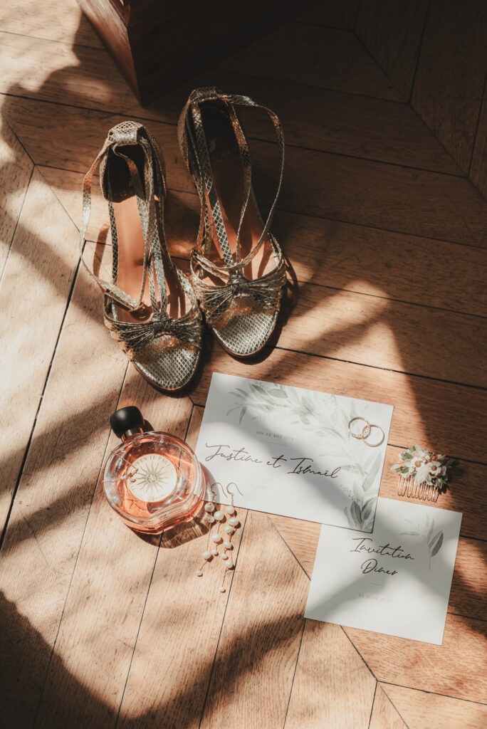 Accessoires de mariage de Justine et Ismaël sur un parquet baigné de lumière naturelle.